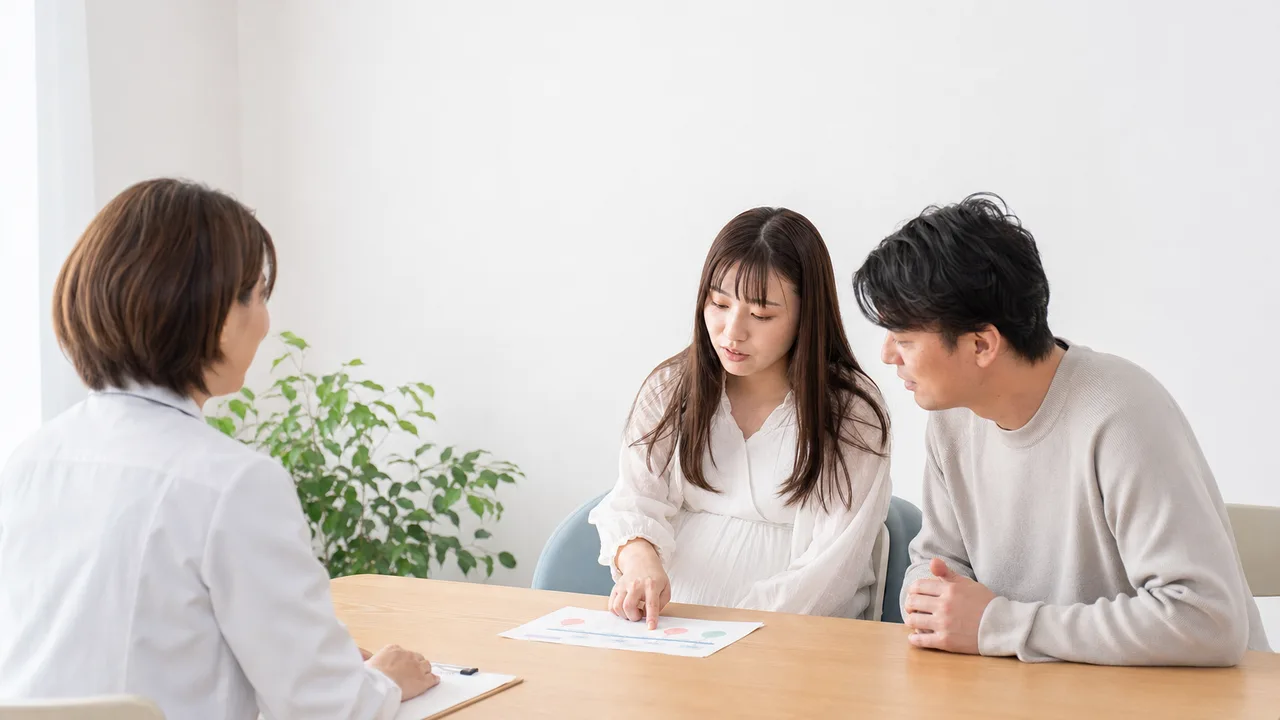 産婦人科で相談する日本人妊婦（横長・コピースペース）。産婦人科、妊婦健診、妊娠、医療相談の記事向け素材です。