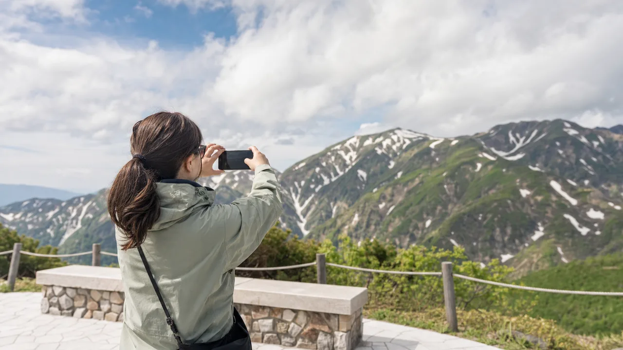 富山の山岳景観を楽しむ旅行者（横長・コピースペース）。富山旅行、立山、山岳観光、北陸旅行の記事や案内に使える商用素材です。