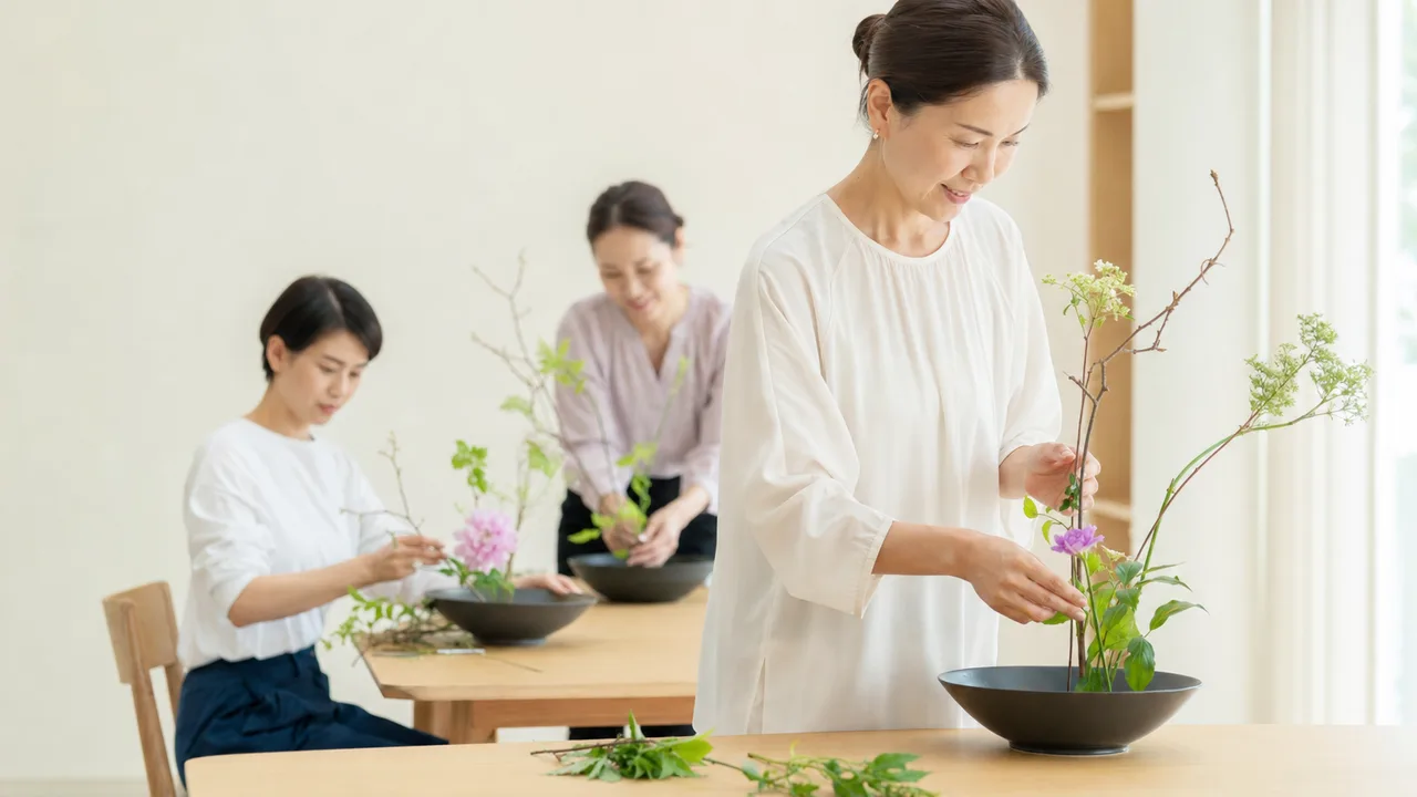 生け花を学ぶ日本人（横長・コピースペース）。生け花、華道、花の教室、伝統文化の記事や案内に使える商用素材です。