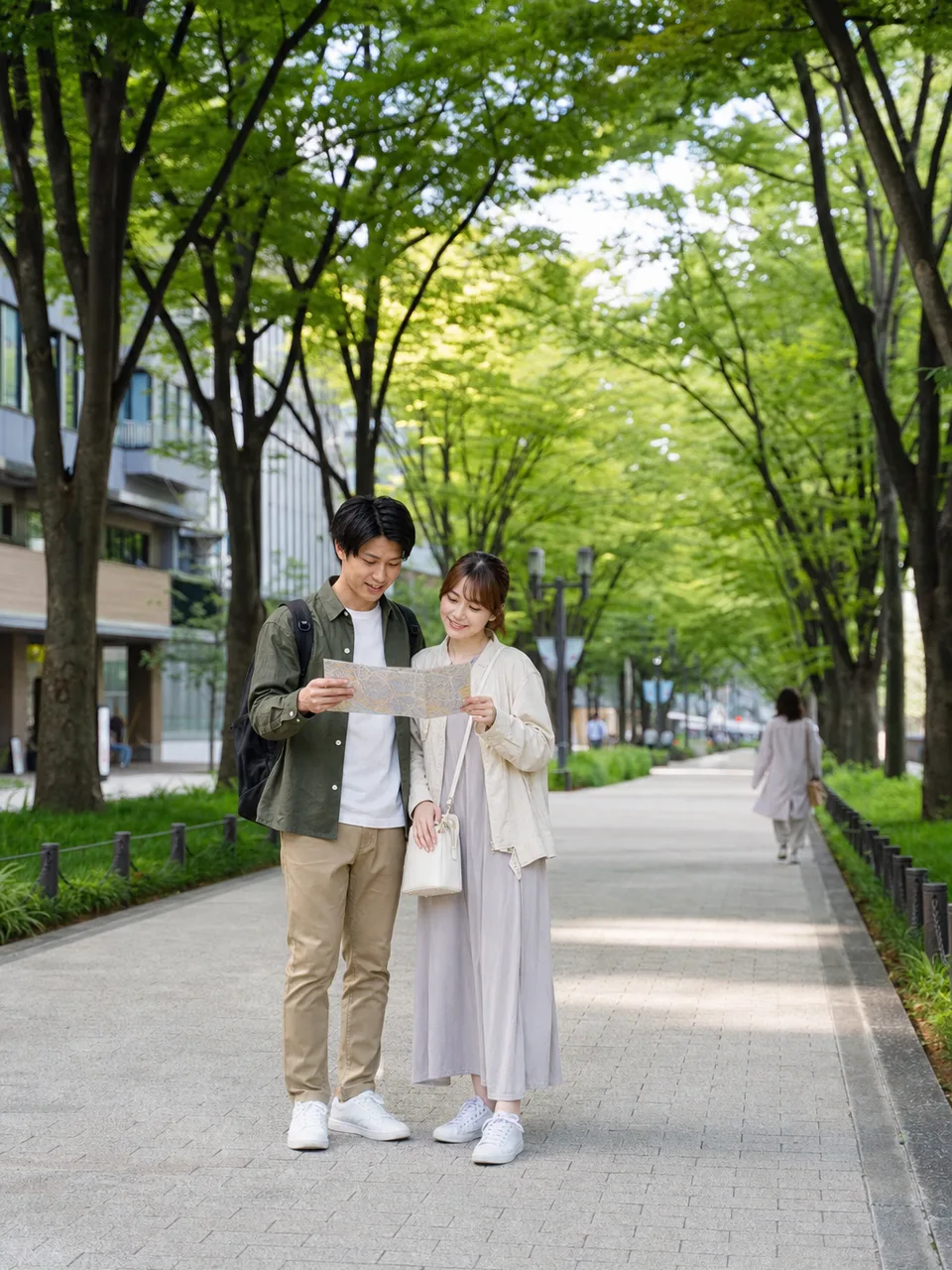 仙台の緑ある街を歩く日本人旅行者（自然な縦位置写真）。仙台、東北旅行、街歩き、都市観光の記事向け素材です。