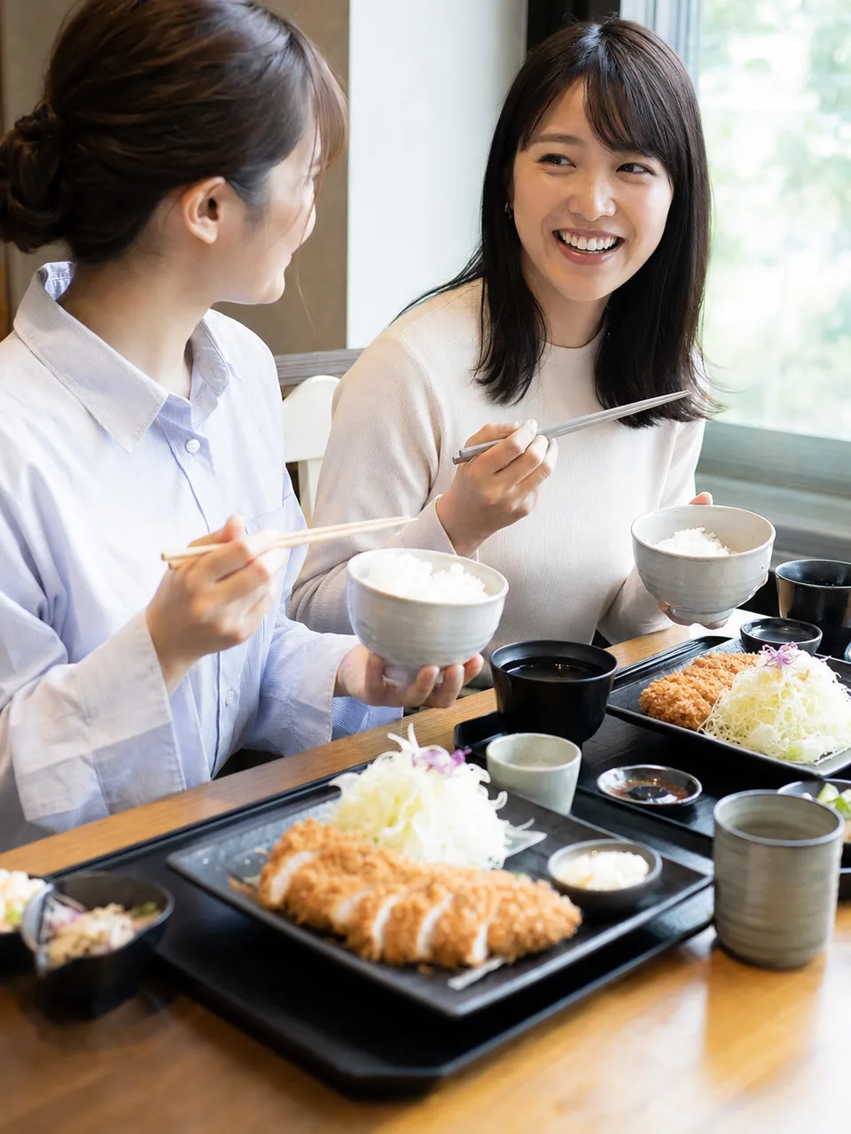 とんかつ定食を楽しむ日本人（自然な縦位置写真）。とんかつ、定食、和食、外食の記事向け素材です。