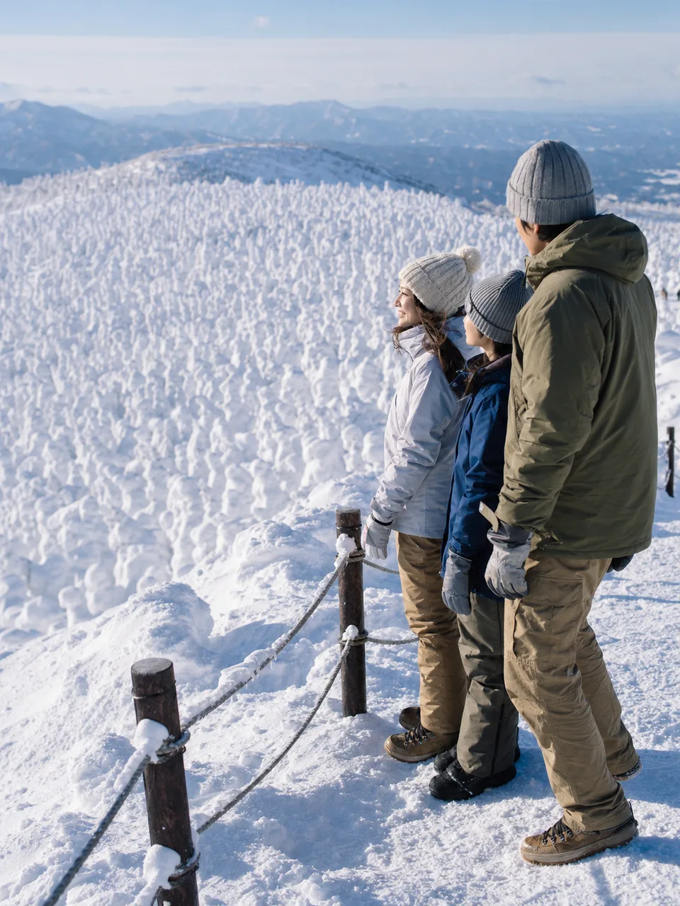 山形の樹氷を安全に楽しむ旅行者（自然な縦位置写真）。山形旅行、樹氷、雪景色、東北旅行の記事や案内に使える商用素材です。