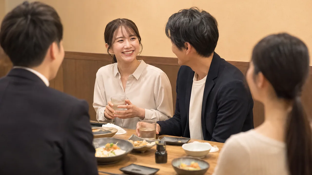 居酒屋で食事を楽しむ日本人同僚（横長・コピースペース）。居酒屋、懇親会、外食、仕事帰りの交流を表現できる素材です。