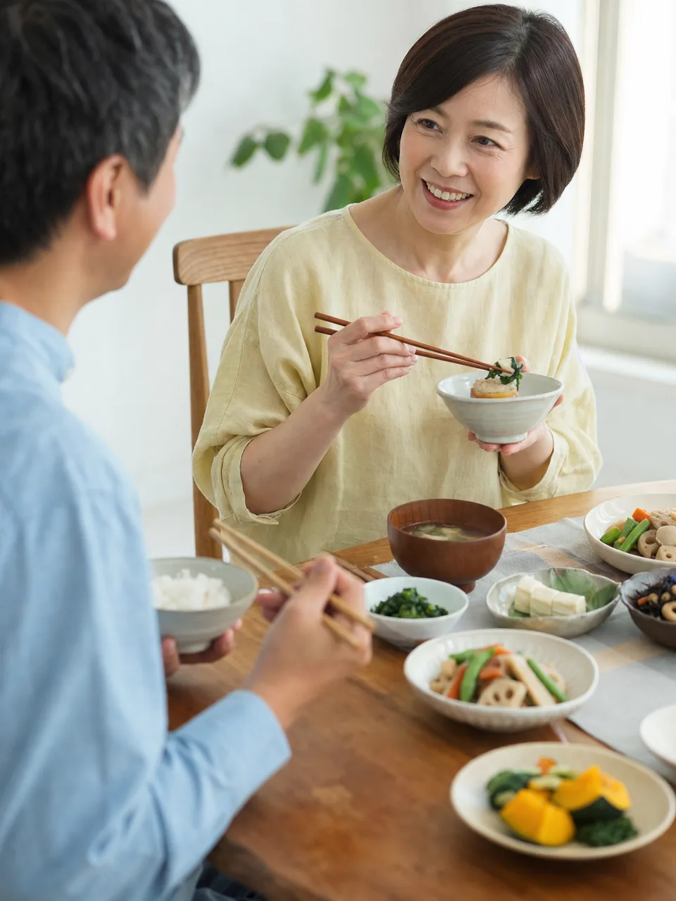 植物性の和食を楽しむ日本人（自然な縦位置写真）。プラントベース、植物性食品、和食、豆腐料理の記事や案内に使える商用素材です。
