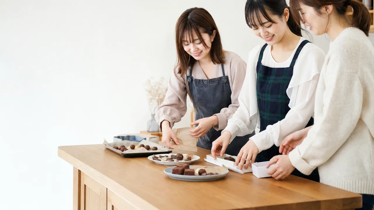 バレンタインの贈り物を作る日本人（横長・コピースペース）。バレンタイン、手作りお菓子、友情、冬のイベントの記事向け素材です。