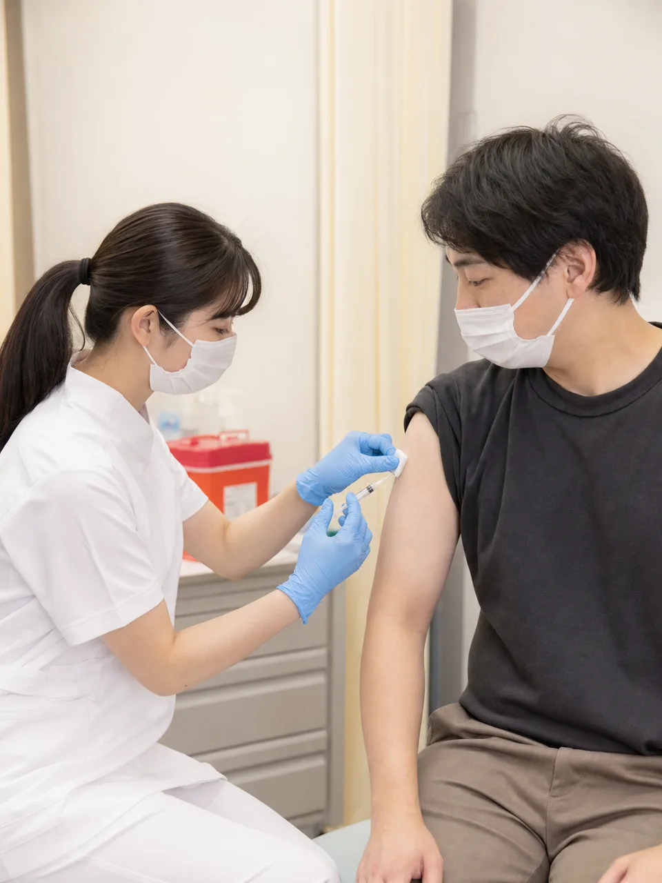 予防接種を受ける日本人成人（自然な縦位置写真）。予防接種、ワクチン、感染症対策、医療の記事向け素材です。