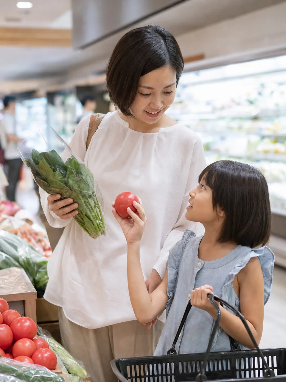 スーパーで食材を選ぶ日本人家族（自然な縦位置写真）。スーパー、買い物、家計、食生活の記事に使える日常素材です。