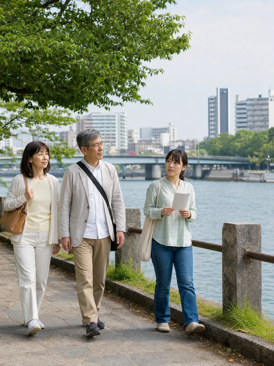 広島の水辺を歩く日本人旅行者（自然な縦位置写真）。広島、平和学習、国内旅行、水辺の街の記事向け素材です。