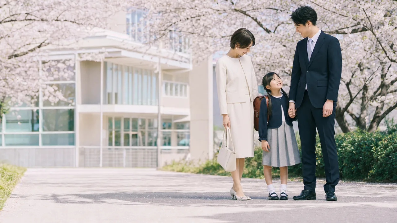 小学校の入学式を迎える親子（横長・コピースペース）。春、学校、子育て、自治体の案内に使える、日本の入学式の親子素材です。