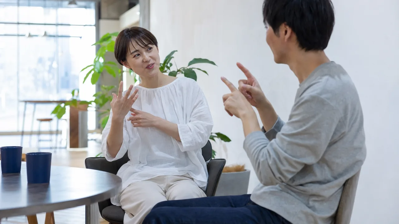 手話で会話する日本人（横長・コピースペース）。手話、聴覚障害、コミュニケーション、共生の記事向け素材です。