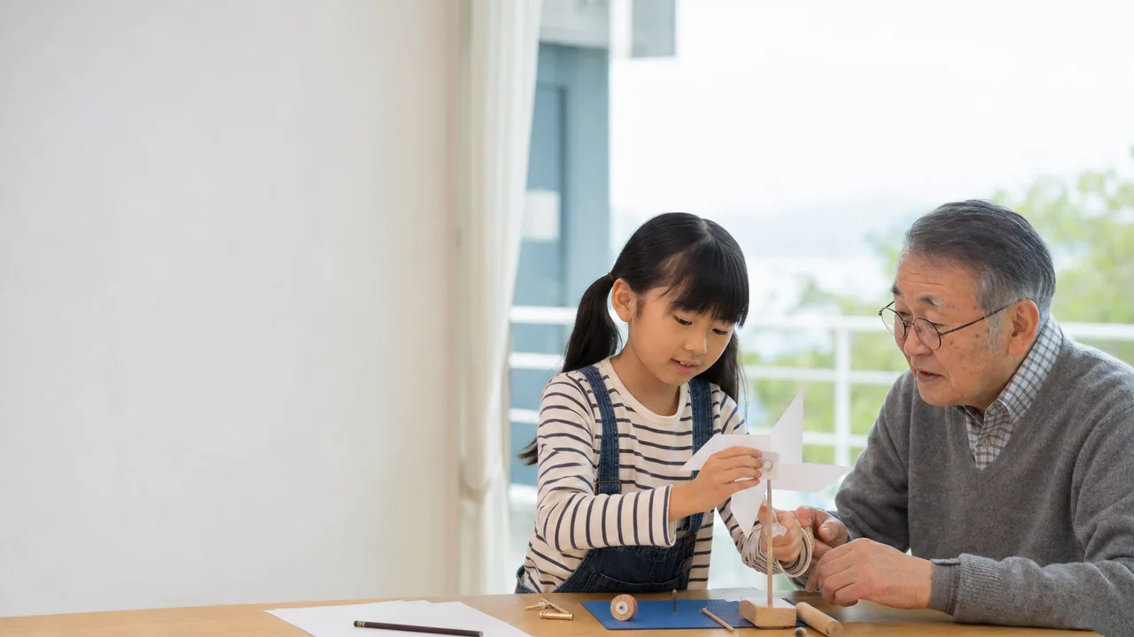 工作を楽しむ日本人の祖父と孫娘（横長・コピースペース）。祖父と孫娘、世代間交流、工作、家族の記事向け素材です。
