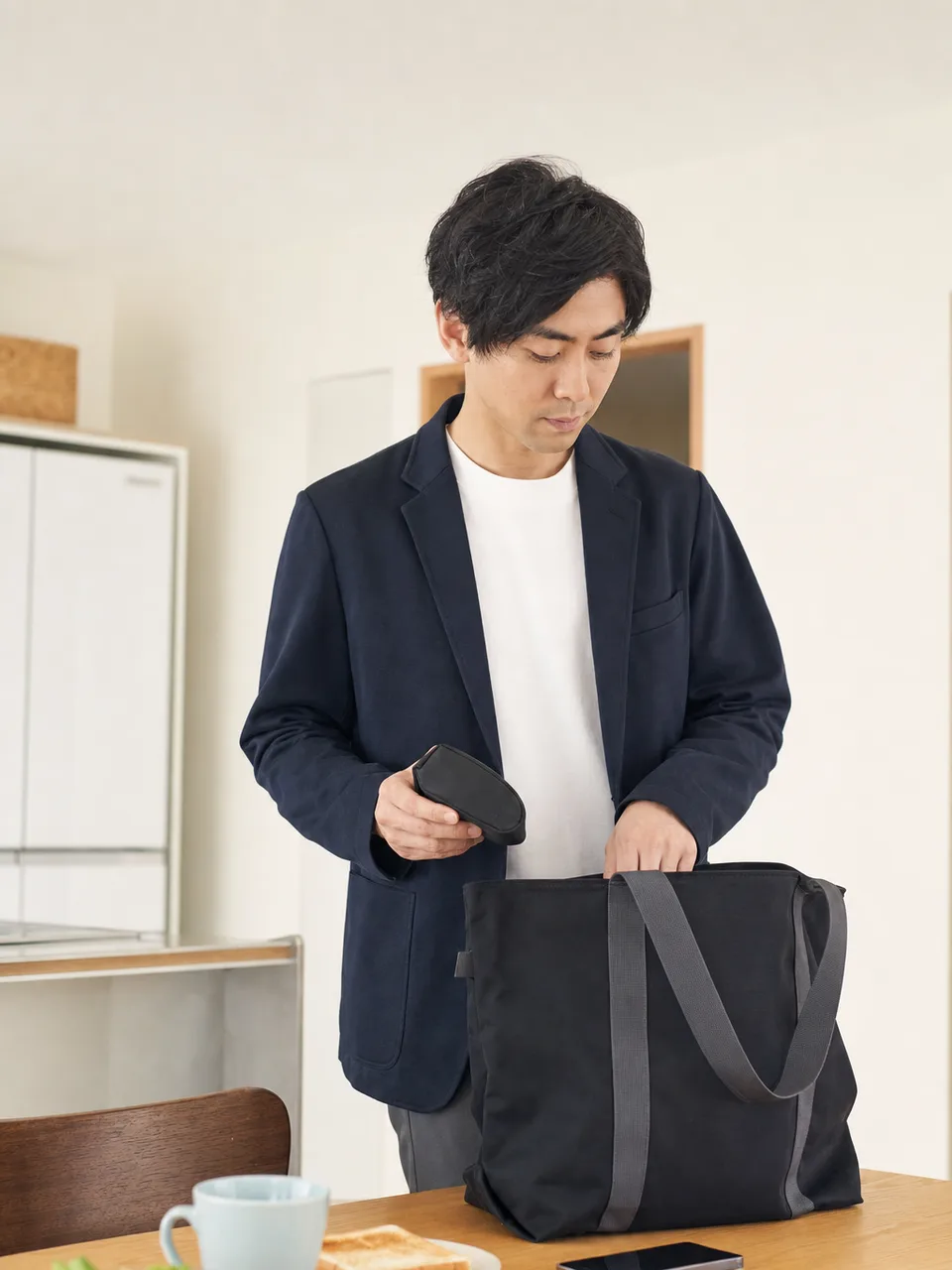朝の支度をする一人暮らしの日本人（自然な縦位置写真）。一人暮らしの朝支度、平日のモーニングルーティン、朝の支度、一人暮らしの記事や案内に使える商用素材です。