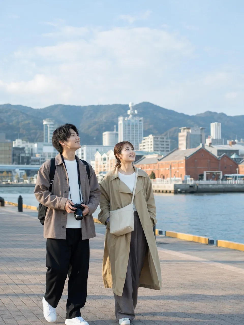 神戸の港を楽しむ日本人旅行者（自然な縦位置写真）。神戸、港町、関西旅行、都市観光の記事向け素材です。