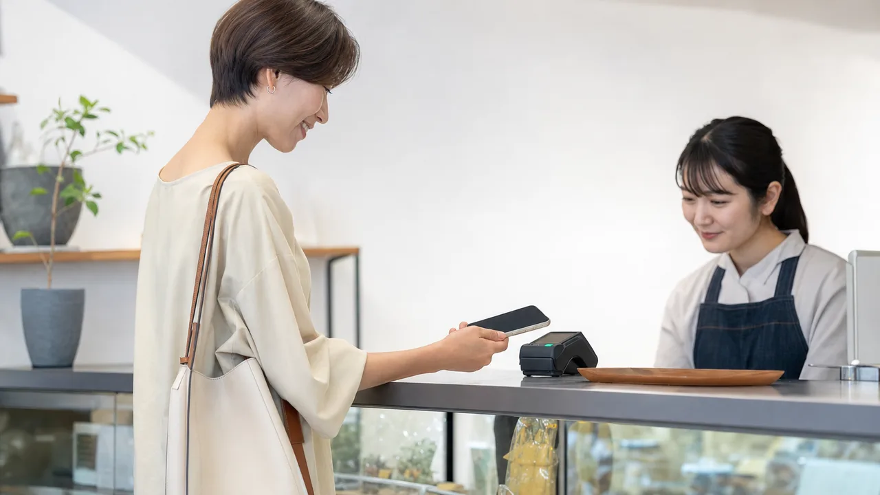電子決済を利用する日本人の買い物客（横長・コピースペース）。電子決済、キャッシュレス、買い物、小売の記事向け素材です。