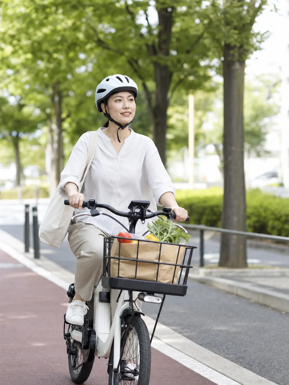 電動自転車で買い物に行く日本人（自然な縦位置写真）。電動自転車で買い物、電動アシスト自転車、自転車の買い物、ヘルメットの記事や案内に使える商用素材です。