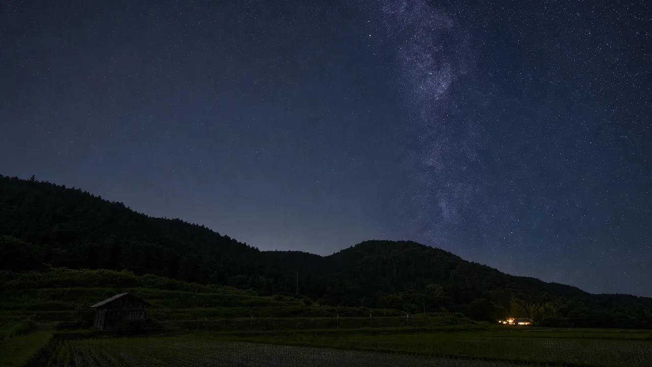 日本の里山に広がる星空（横長・余白背景）。星空、夜空、里山、自然背景のデザインに使える素材です。
