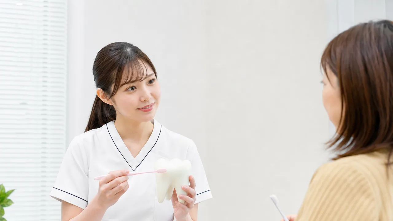 歯磨きを指導する日本人歯科衛生士（横長・コピースペース）。歯科衛生士の歯磨き指導、ブラッシング指導、歯科衛生士、予防歯科の記事や案内に使える商用素材です。