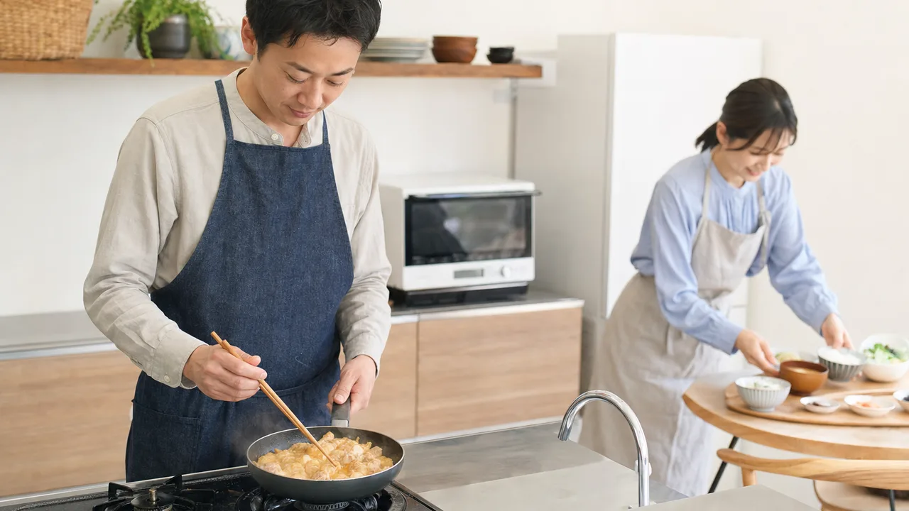 親子丼を作る日本人（横長・コピースペース）。親子丼、丼料理、家庭料理、昼食の記事向け素材です。
