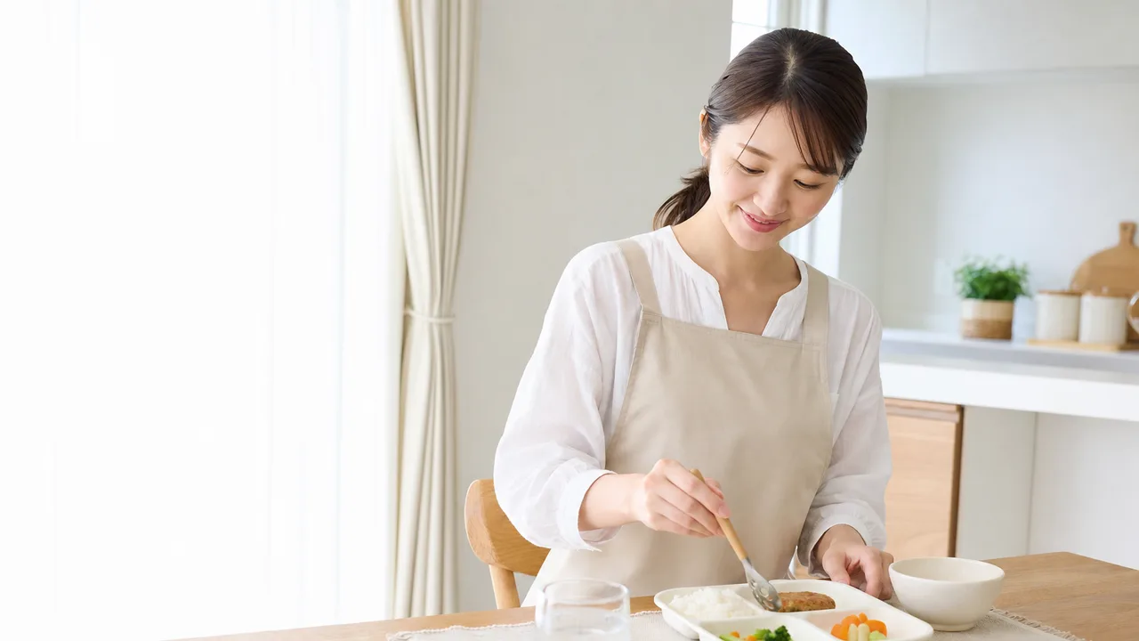 子どもの昼食を盛り付ける日本人（横長・コピースペース）。子どもの昼食、幼児食、食育、家庭料理の記事や案内に使える商用素材です。