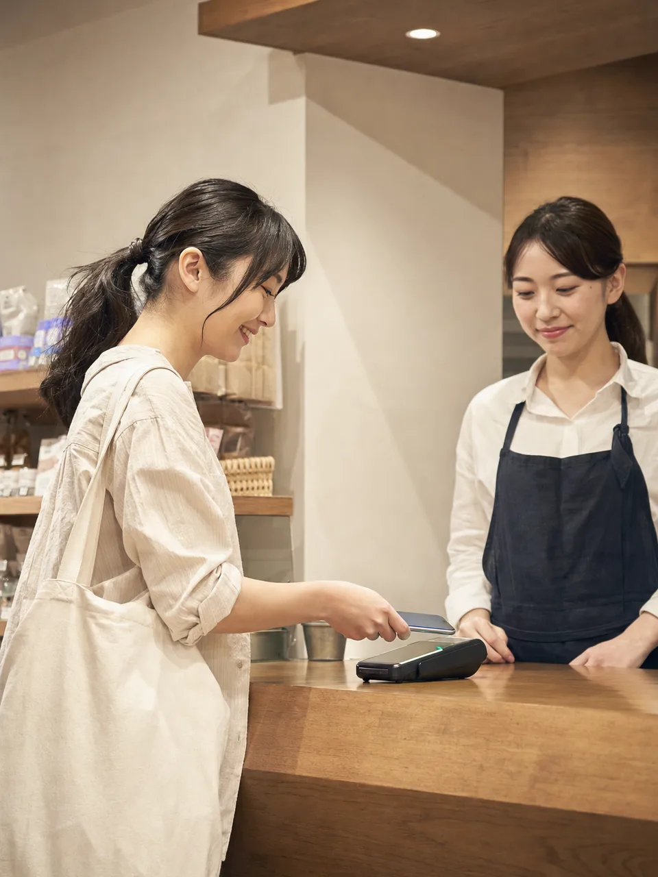 電子決済を利用する日本人の買い物客（自然な縦位置写真）。電子決済、キャッシュレス、買い物、小売の記事向け素材です。