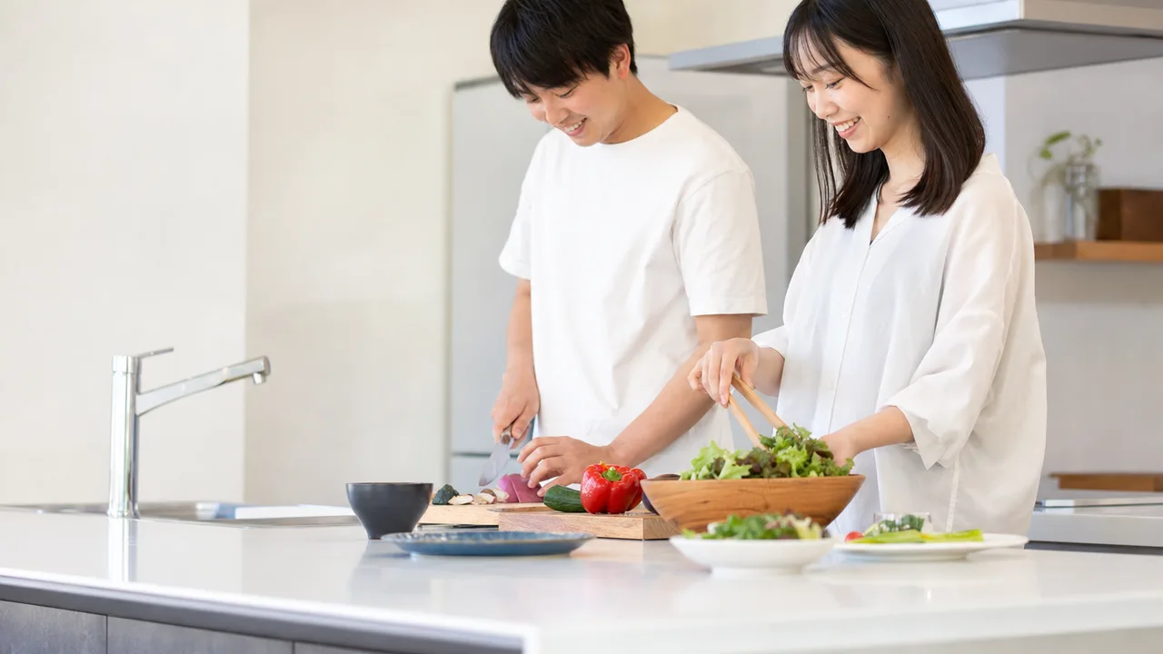 一緒に料理する日本人きょうだい（横長・コピースペース）。成人きょうだいの料理、きょうだいで作る家庭料理、きょうだい、兄弟姉妹の記事や案内に使える商用素材です。