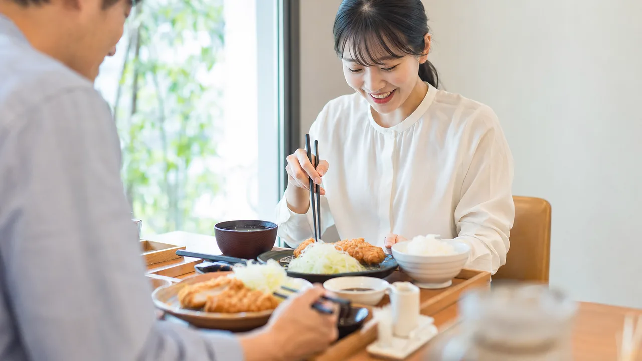 とんかつ定食を楽しむ日本人（横長・コピースペース）。とんかつ、定食、和食、外食の記事向け素材です。