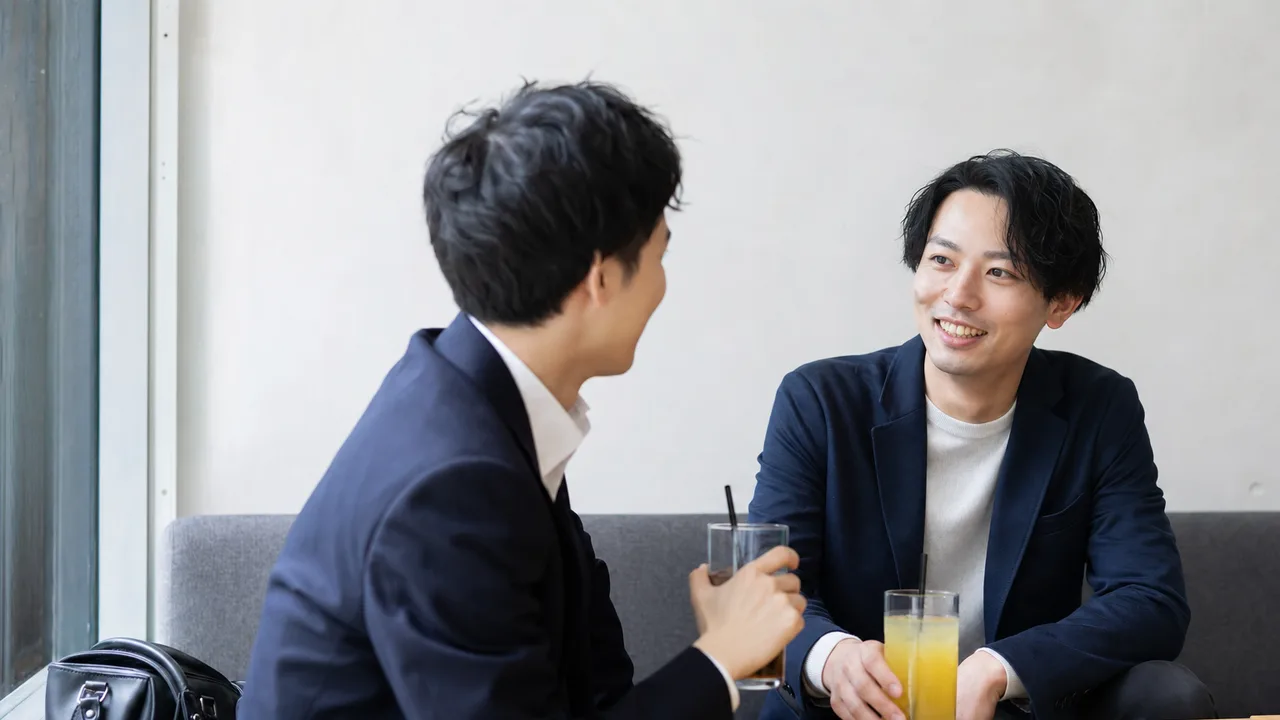 仕事帰りに話す日本人の友人（横長・コピースペース）。仕事帰りのノンアルカフェ、退勤後の友人との会話、仕事帰り、友人の記事や案内に使える商用素材です。