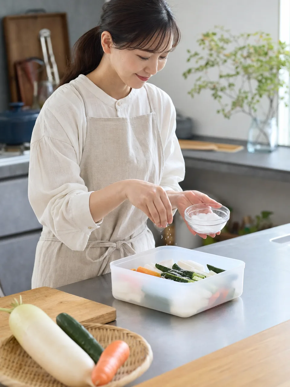 家庭で漬物を仕込む日本人（自然な縦位置写真）。漬物作り、発酵食品、保存食、野菜の記事や案内に使える商用素材です。