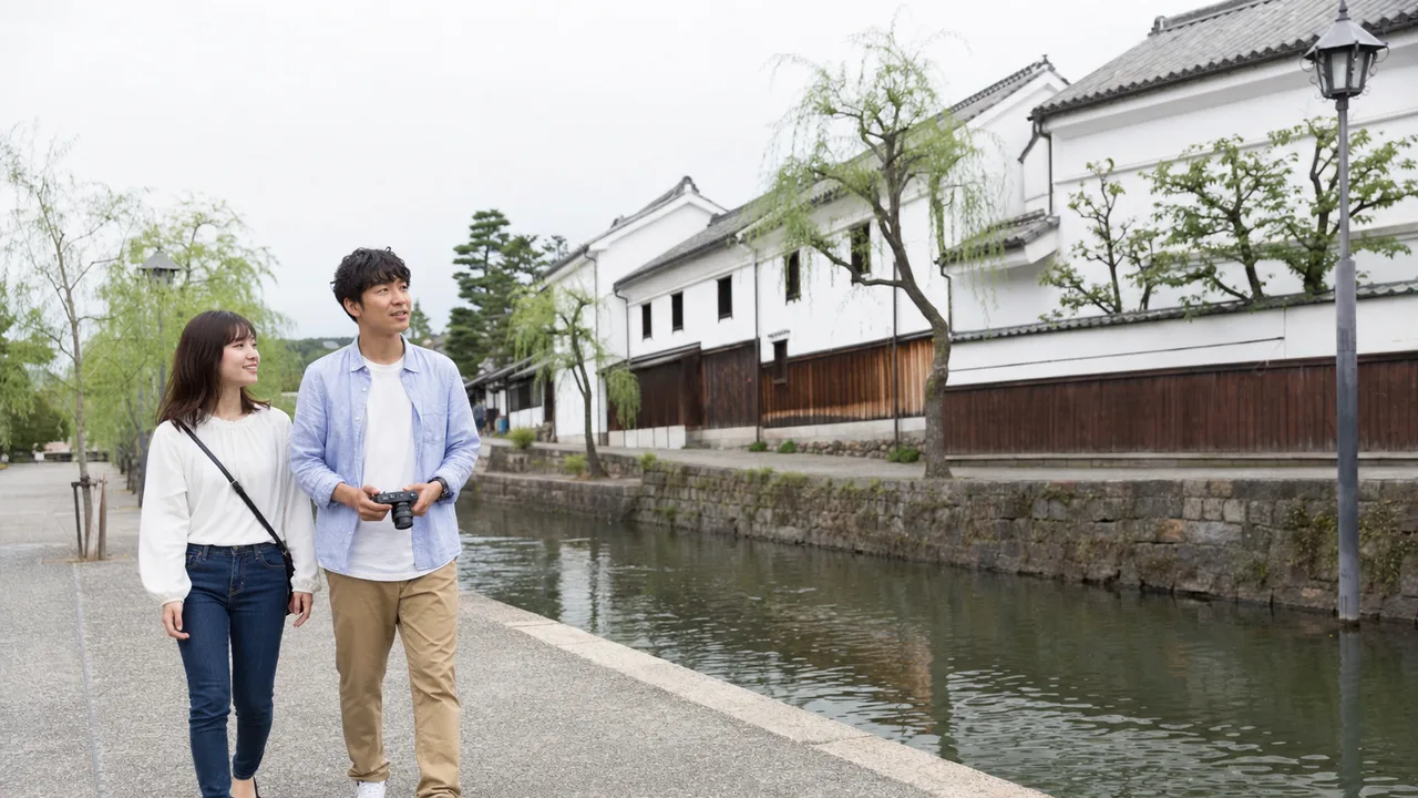 岡山の白壁の町を歩く旅行者（横長・コピースペース）。岡山旅行、倉敷、白壁の町、中国地方旅行の記事や案内に使える商用素材です。