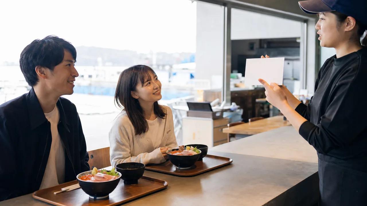 海鮮丼を味わう日本人旅行者（横長・コピースペース）。海鮮丼、魚介、地域の食、旅行の記事向け素材です。