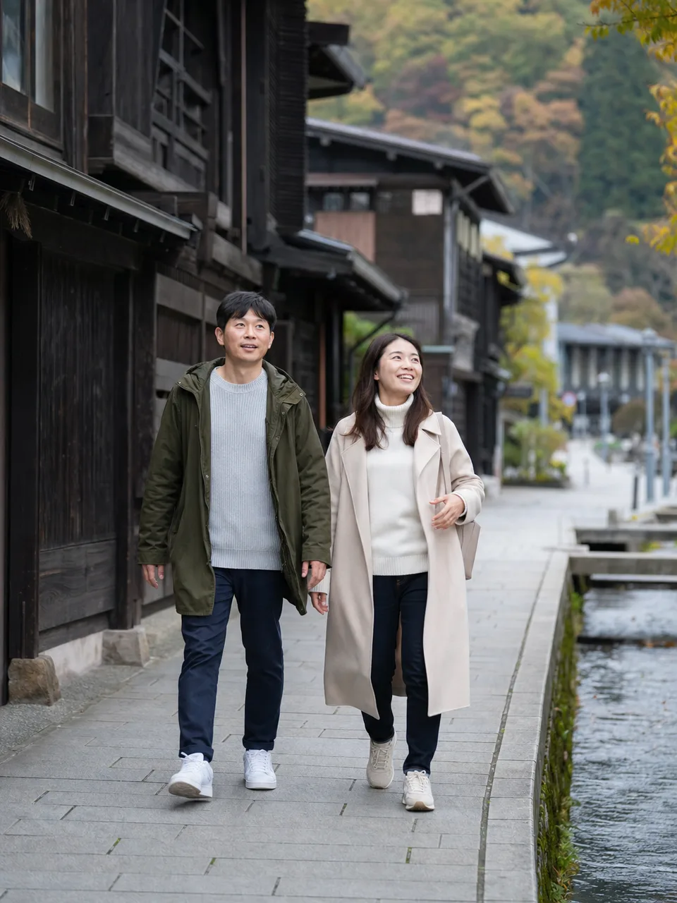 秋田の歴史ある町並みを歩く旅行者（自然な縦位置写真）。秋田旅行、歴史的町並み、東北旅行、城下町の記事や案内に使える商用素材です。
