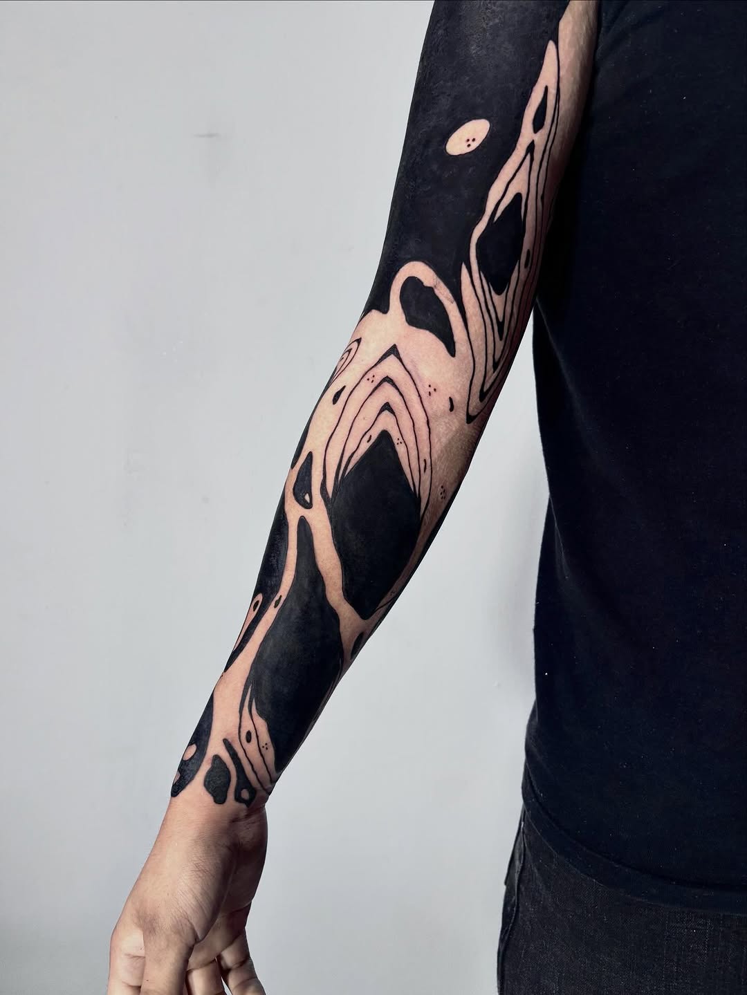 Negro sólido, líneas que fluyen y un diseño que se amarra al brazo desde el hombro hasta la muñeca.
El contraste hace todo: blackout pesado y espacios
