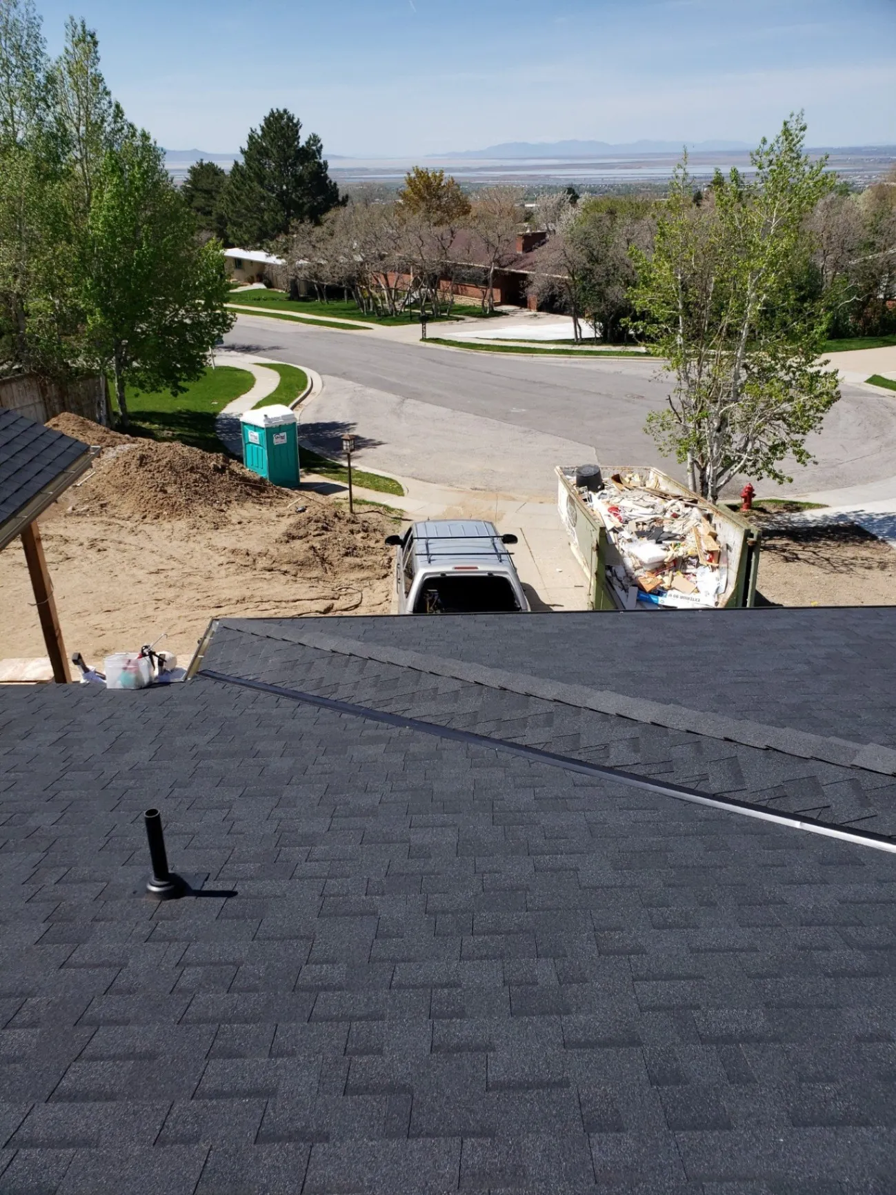 Roof replacement project in South Ogden, UT featuring new dark asphalt shingles and tear-off debris removal by North Point Roofing LLC.