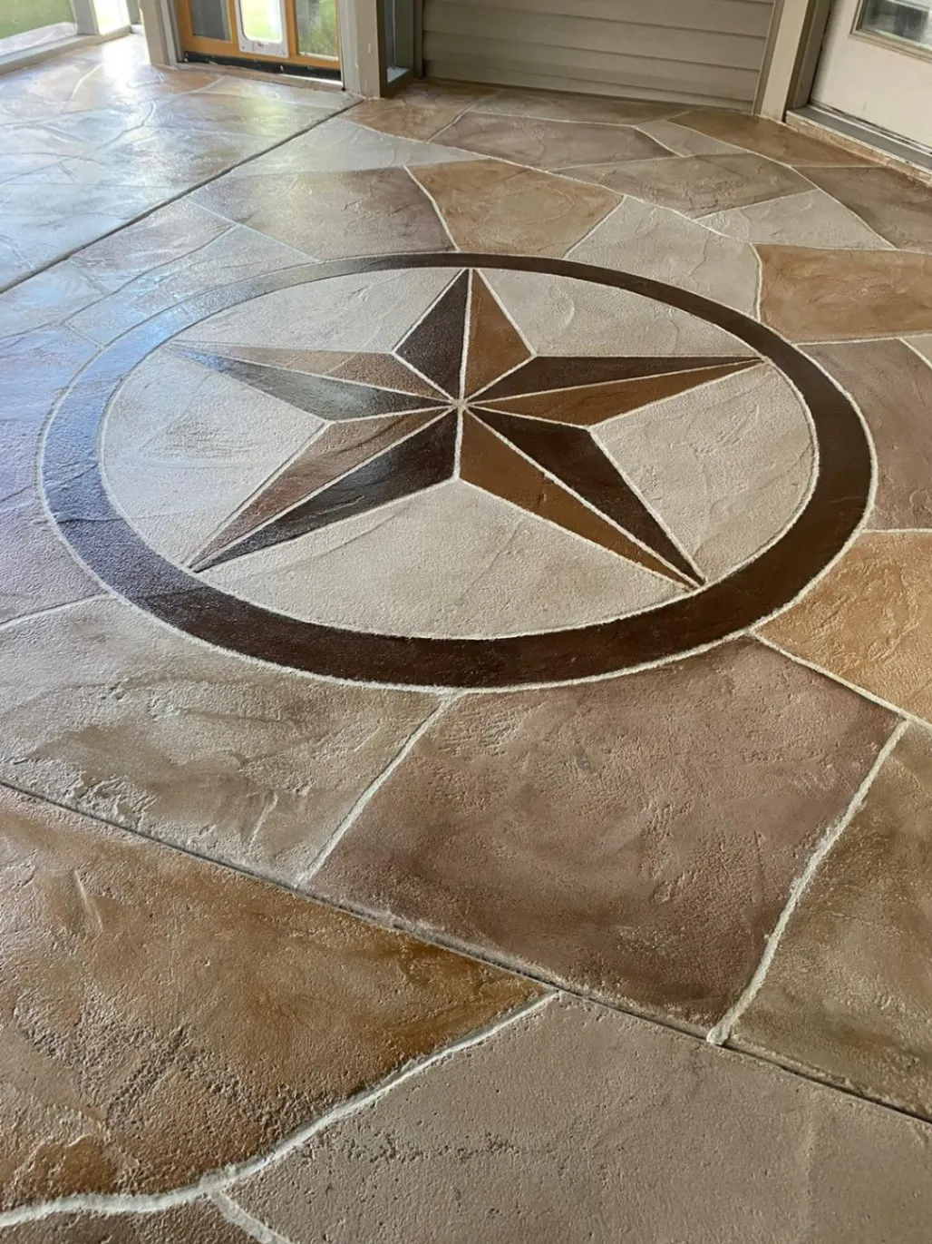 Garage floor with a newly installed gray and black epoxy coating, providing a smooth and durable speckled surface finish.