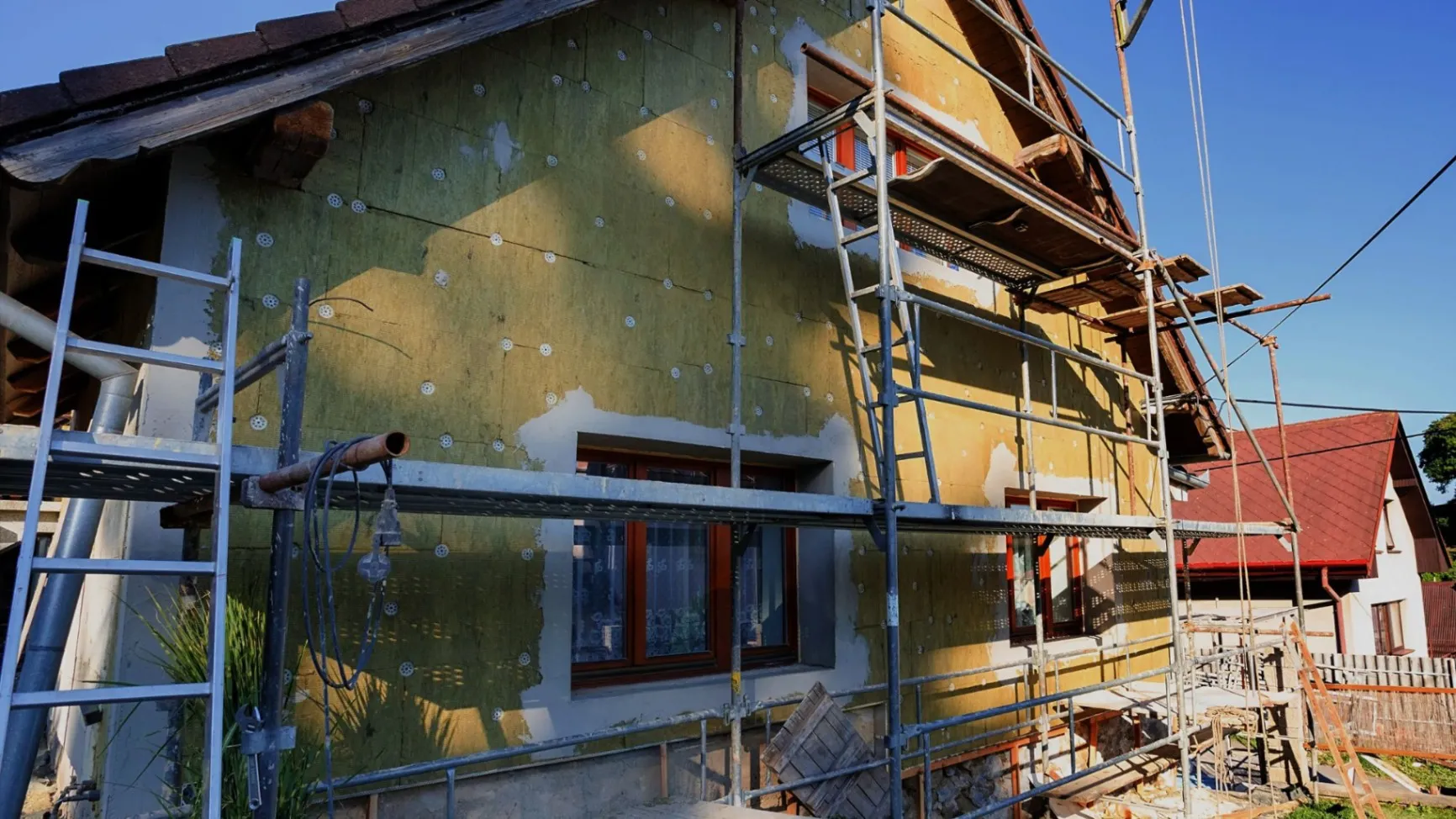 A house under construction with scaffolding and ladders.