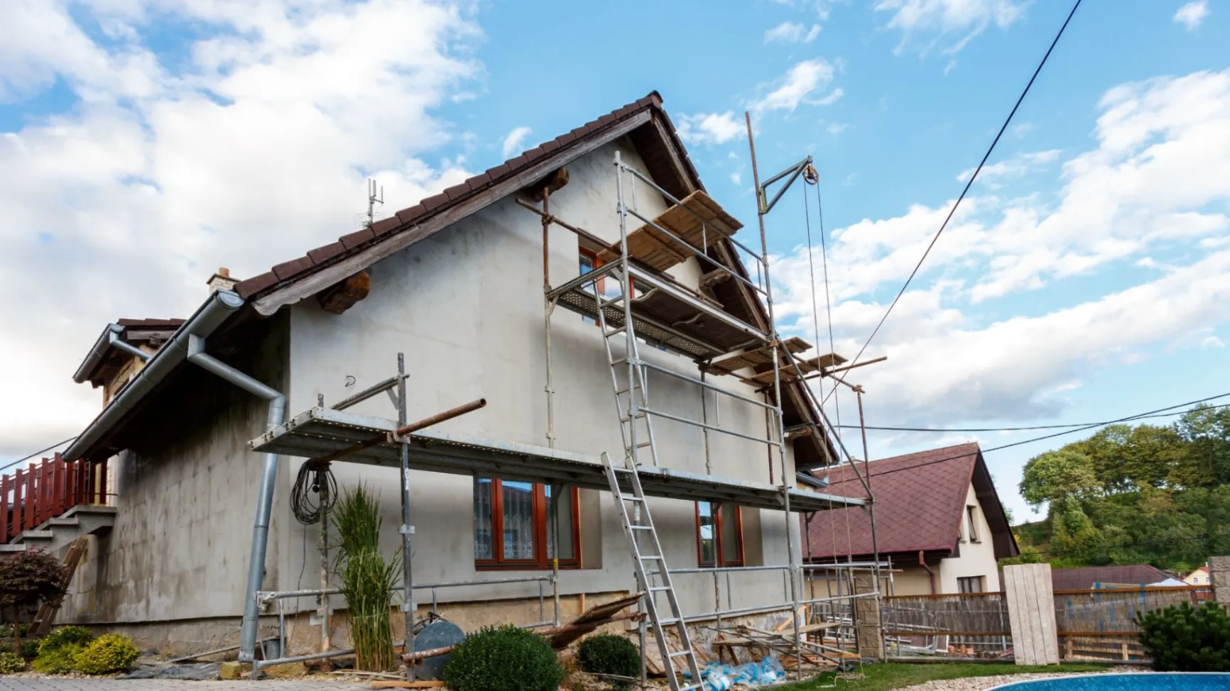 A house with scaffolding and ladders set up against the side, indicating ongoing exterior renovations.