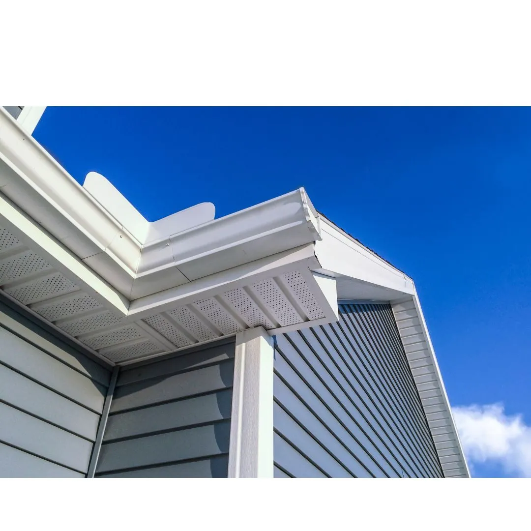 Close-up of a roof corner with white gutters and blue siding under a clear blue sky