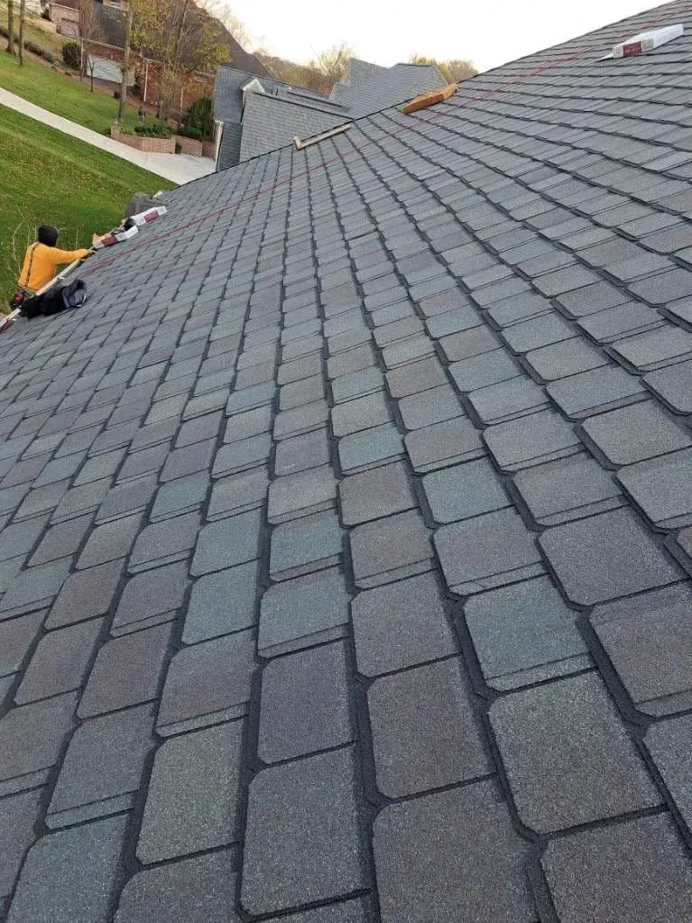 Roofer working on a sloped roof with slate-like asphalt shingles