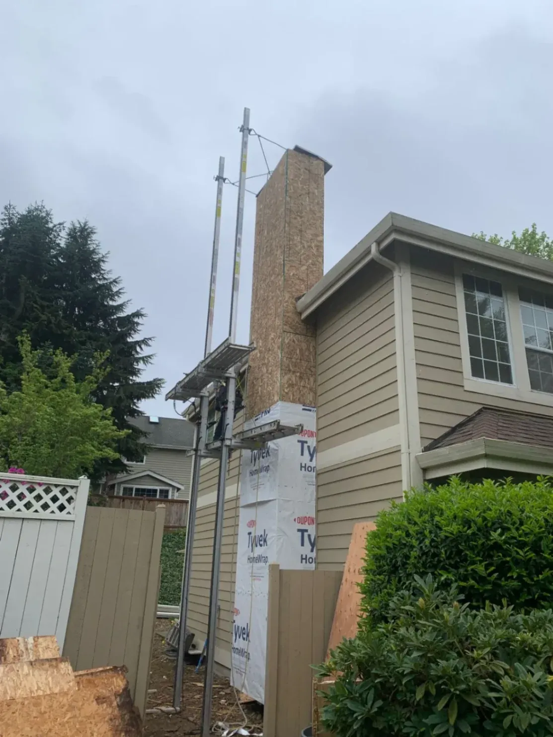 A professional siding contractor repairing damaged wall framing and removing structural wood rot from a house exterior in Mercer Island, WA, before installing new siding.