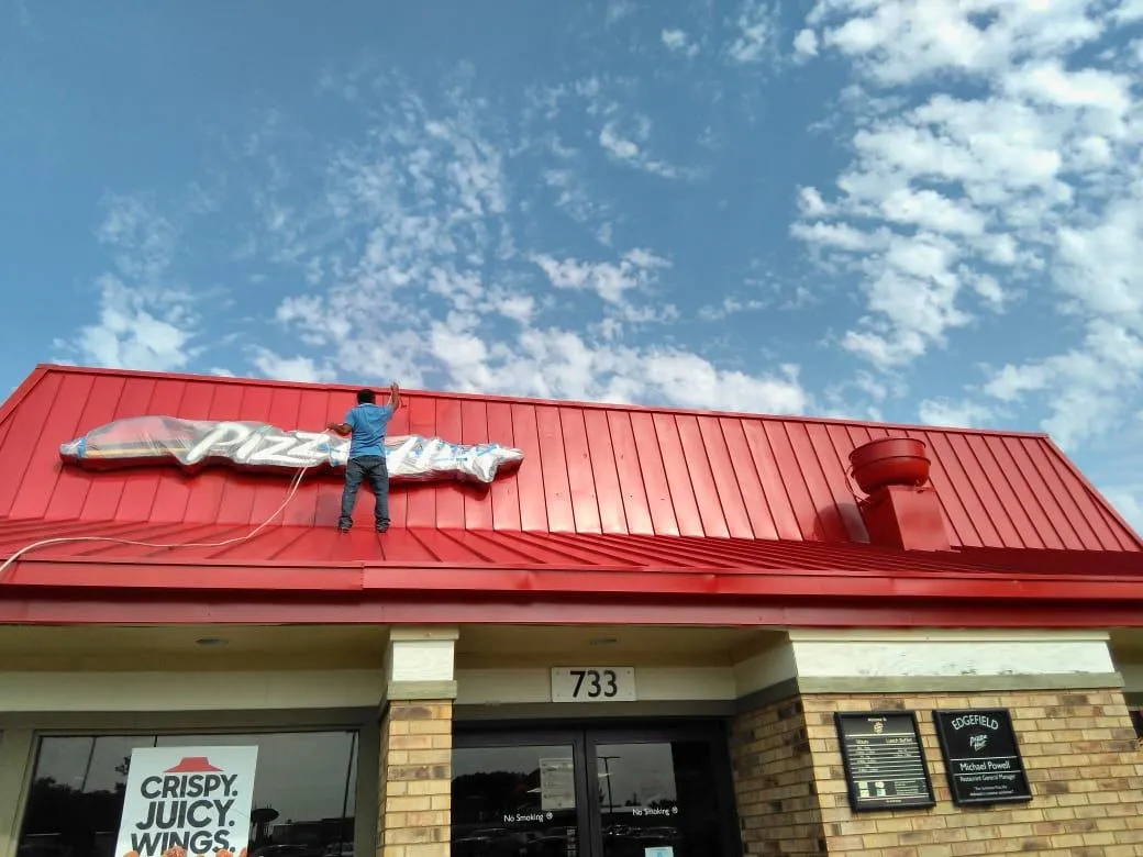 A professional painter near Forest Acres, SC painting the roof of a pizza hut roof