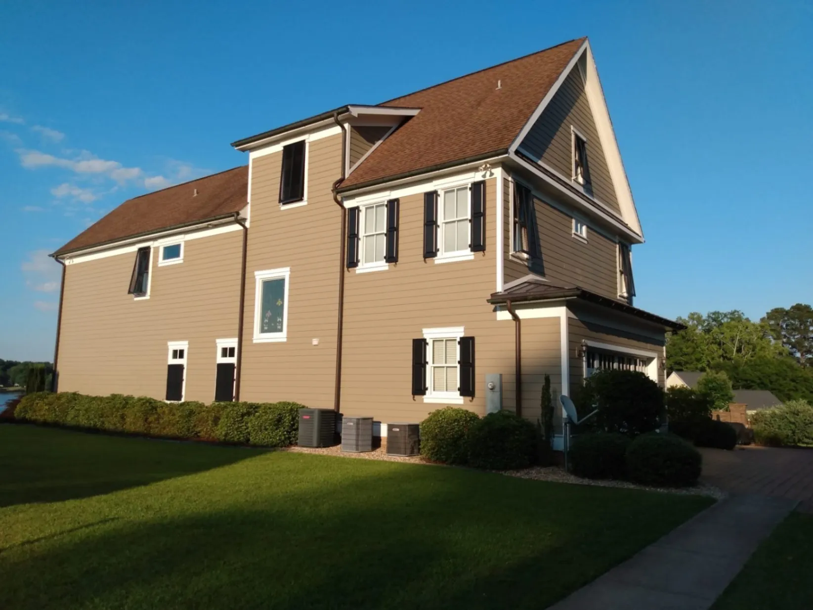 Two-story house with freshly painted tan siding, white trim, and black shutters.