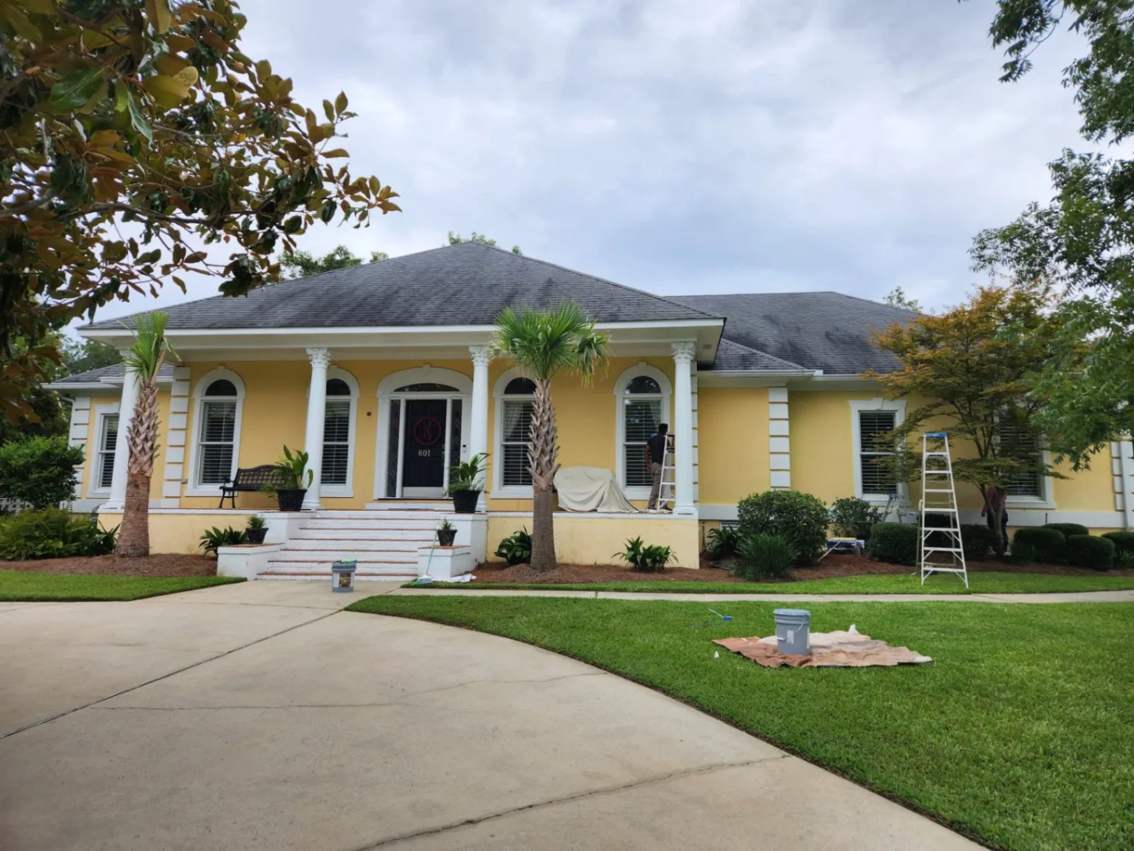 Exterior painting of a residential property, showcasing the preparation and application of paint on the front of the house.