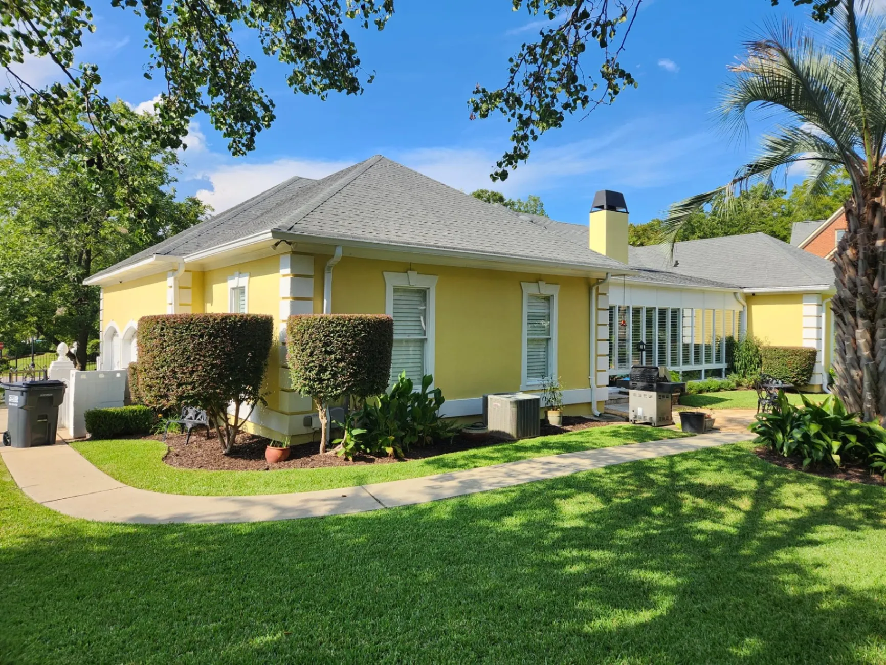 Exterior of a beautifully painted yellow home with clean, sharp lines and vibrant colors, showcasing the exceptional painting work done by Hernández Painting & Renovations LLC.