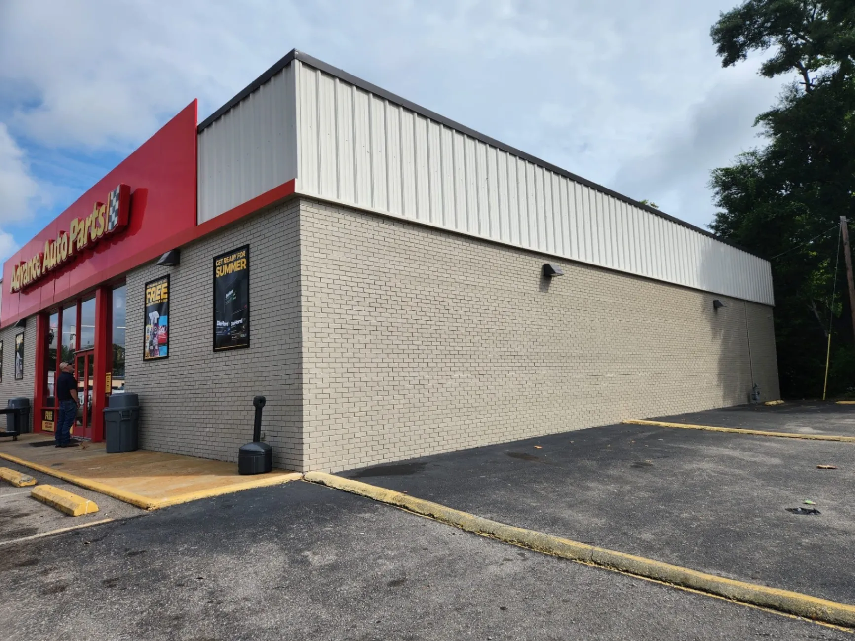 Exterior of an auto parts store with a clean, newly painted brick wall and trim, showcasing a professional and well-maintained look. The paint job highlights the smooth texture and fresh finish on the building's facade.
