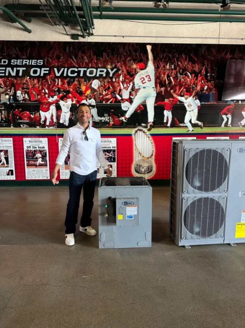 Angel Escobedo stands inside Angel Stadium in Anaheim beside commercial HVAC equipment, ready for an HVAC installation.