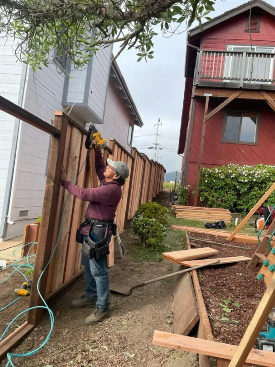 A professional fence builder is working on a wood fence installation