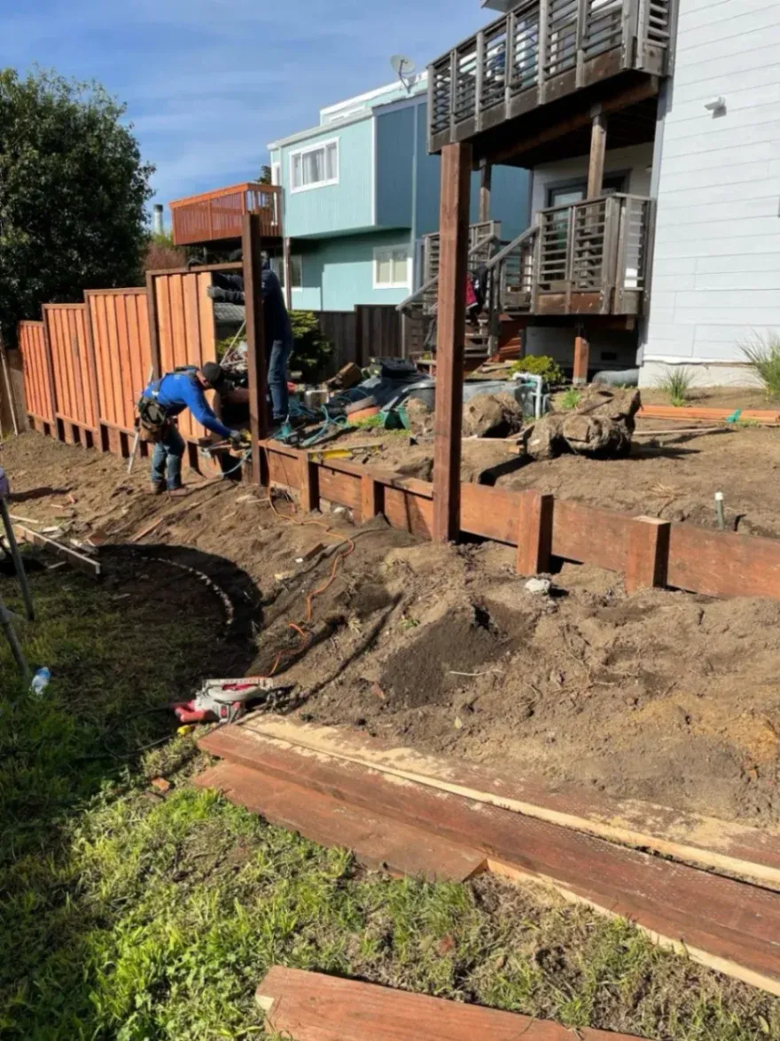 Two hardworking man replacing an old wood  fence