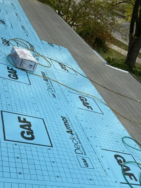 Blue GAF Deck-Armor synthetic roof underlayment installed on a residential roof deck during a roof replacement project.