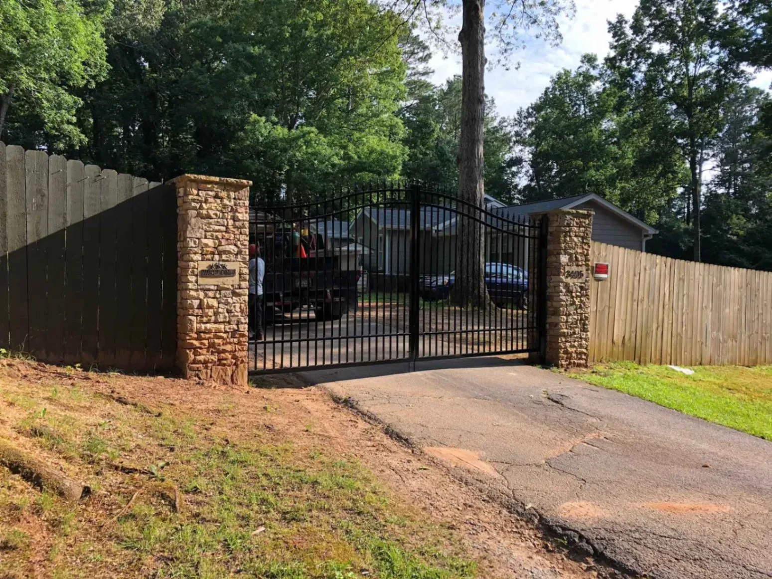 Custom wrought iron security driveway gate with stone pillars fabricated and installed by R&R Construction Services in Roswell, GA.