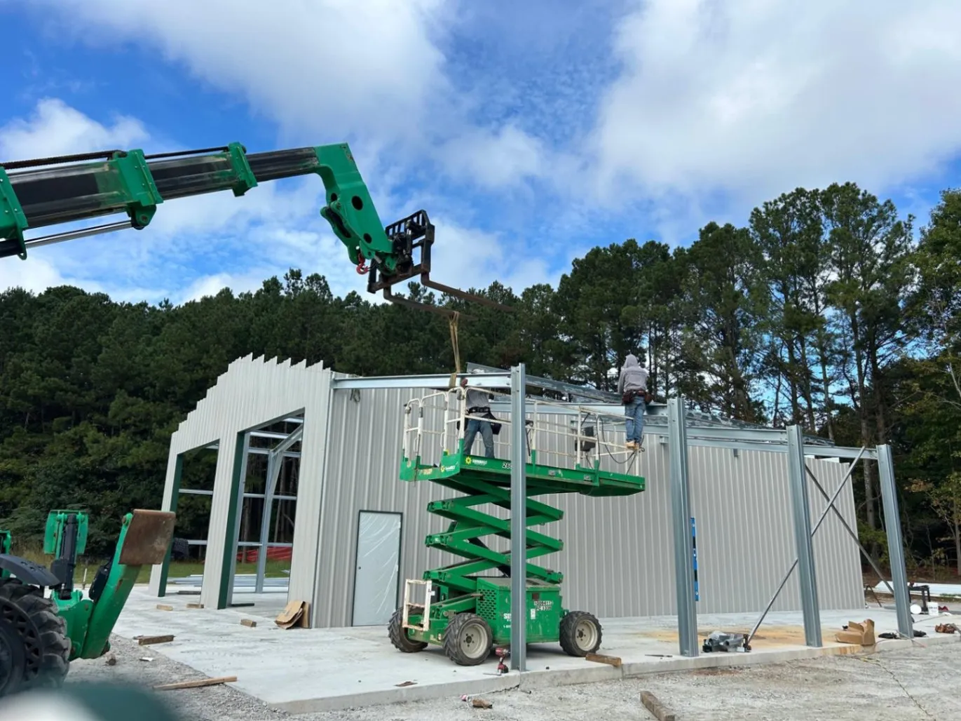 R&R Construction Services - Welding crew on a scissor lift installing roof steel beams with a telehandler forklift at a commercial construction site in Roswell, GA.